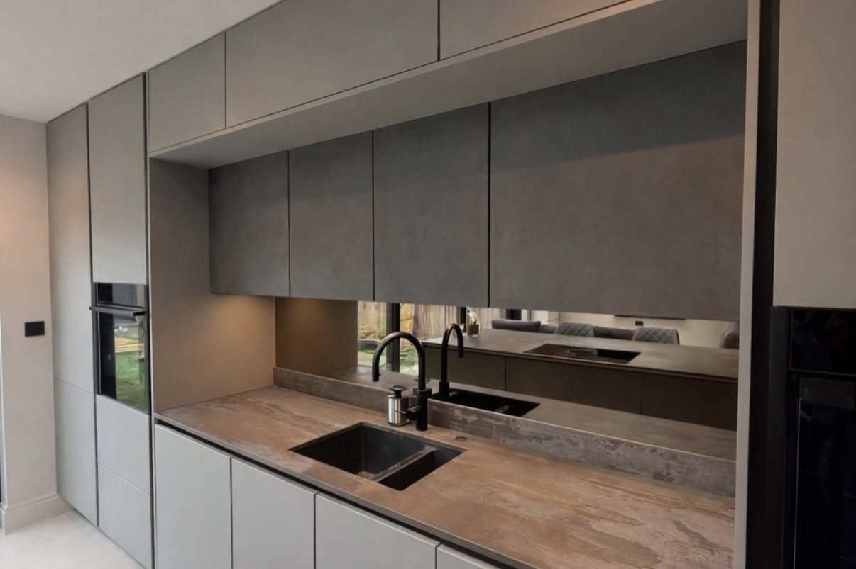 Handleless grey kitchen with integrated appliances and dark sink