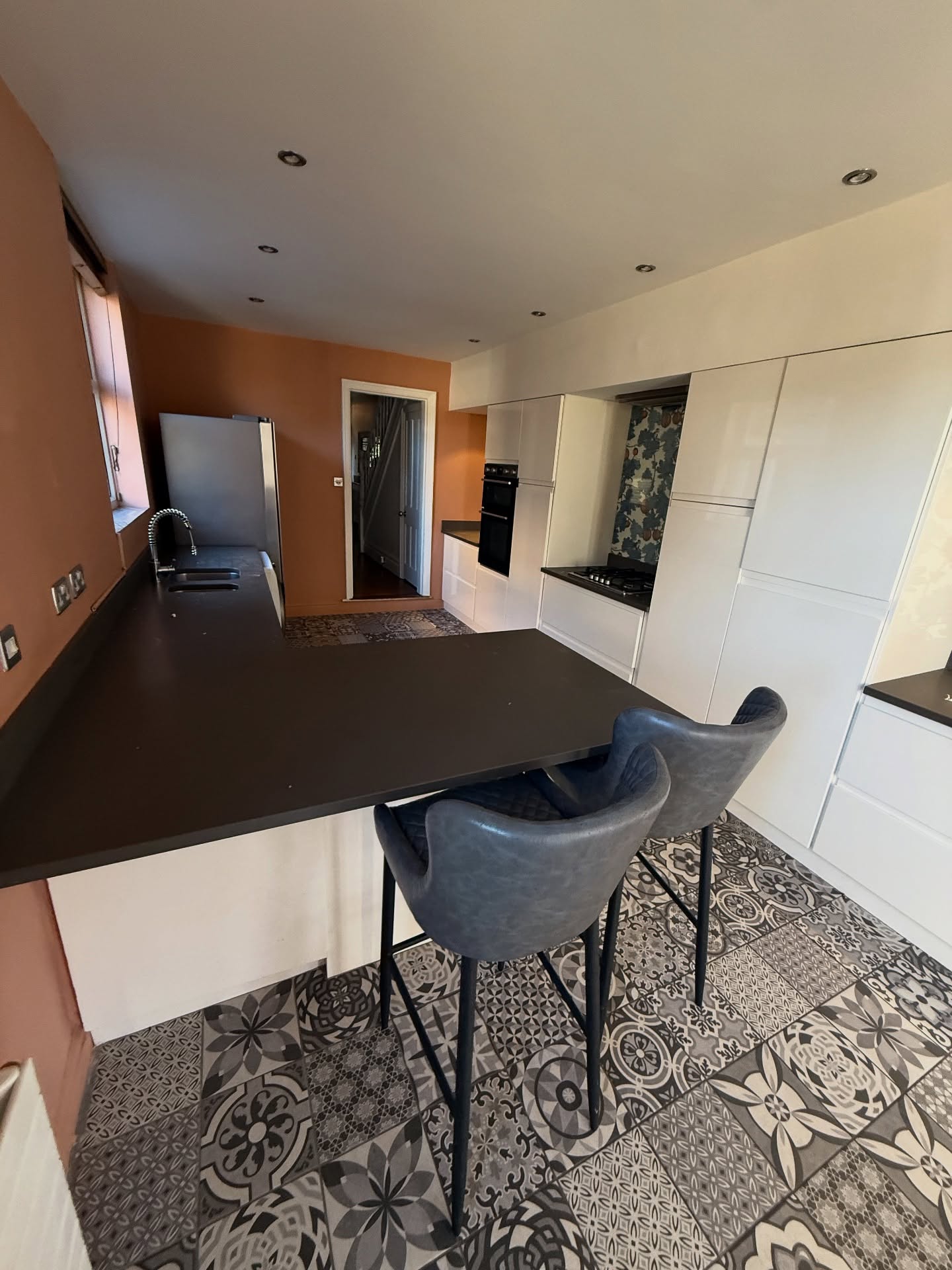 Patterned tile floor with breakfast bar in refurbished kitchen