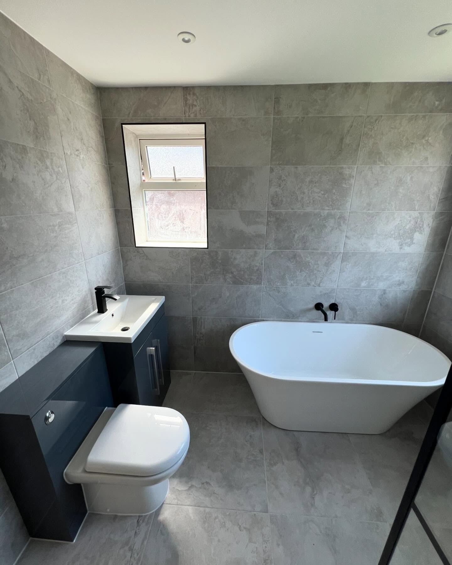 New bathroom with freestanding bath and navy vanity unit
