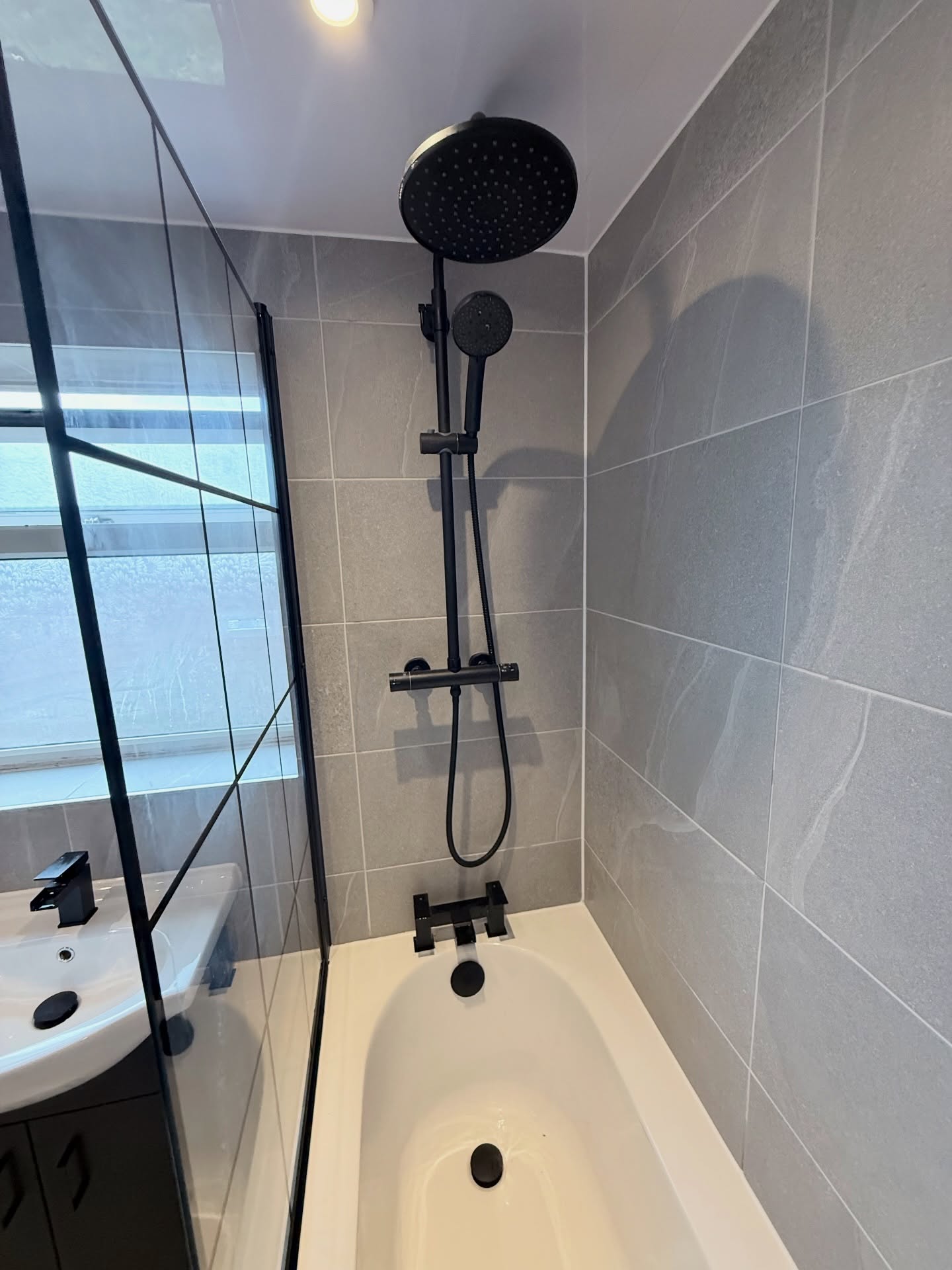 Walk-in shower bathroom with grey tiling and black fittings